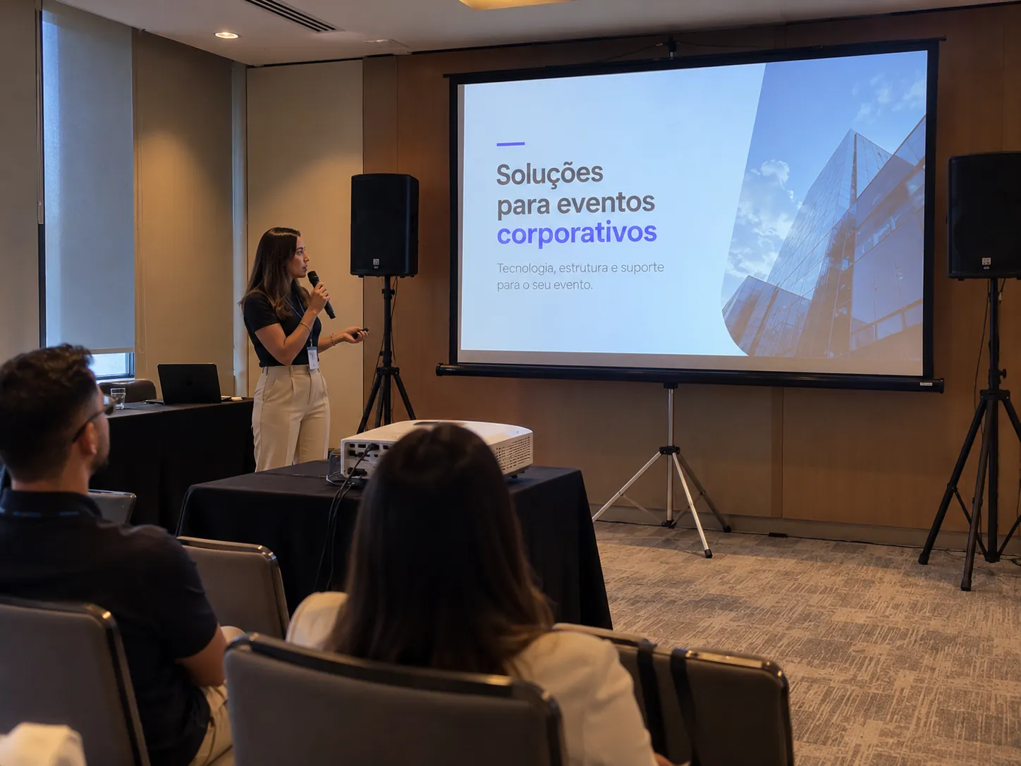 Pequena apresentação corporativa com projetor, telão em tripé e caixas de som compactas
